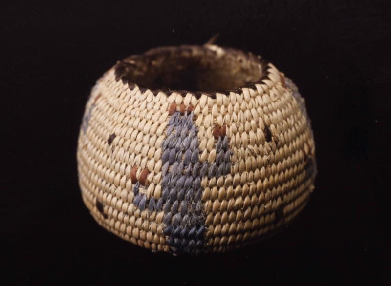 Miniature olla basket; coiled. Design consists of four blue figures which resemble cactii. Colors are natural, blue, brown, and black.